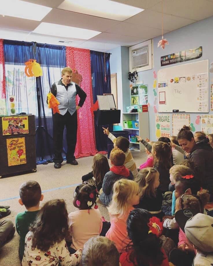 Person performing magic for a group of children in a classroom