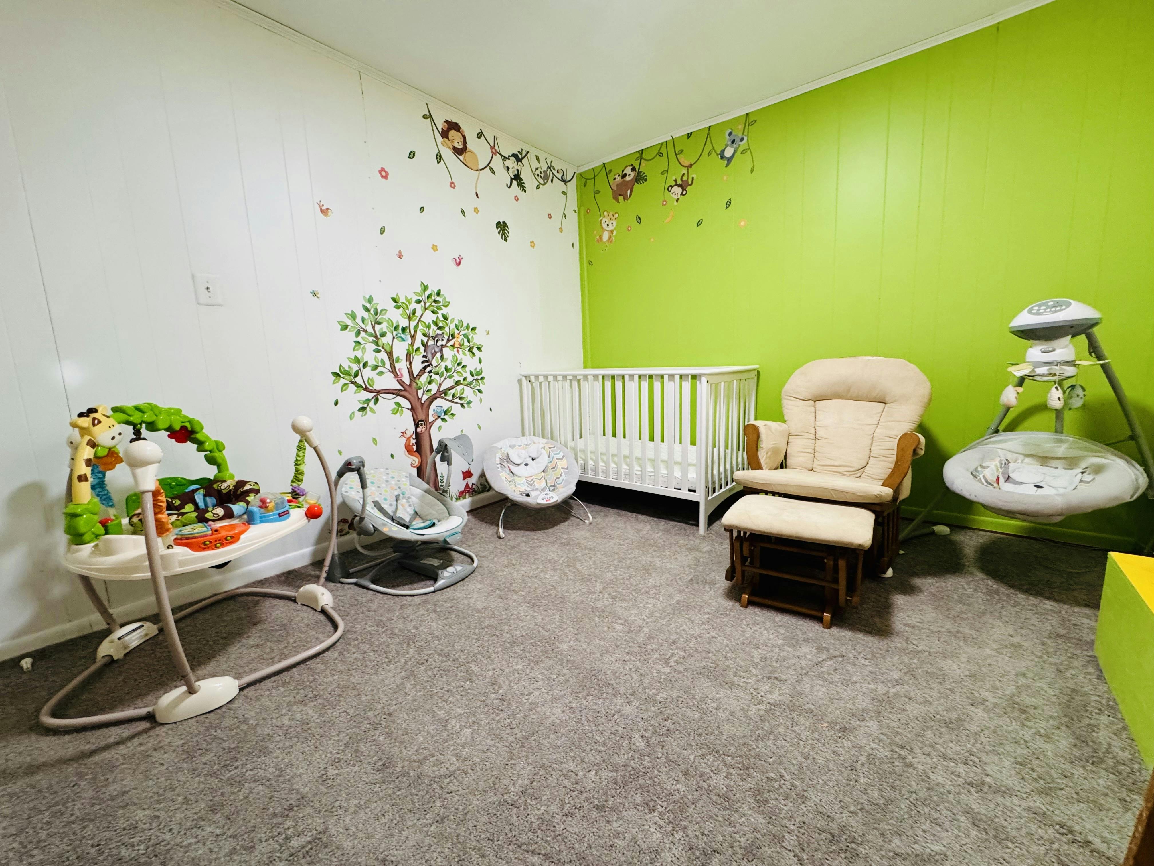 Nursery room with a crib, glider chair, and baby activity equipment