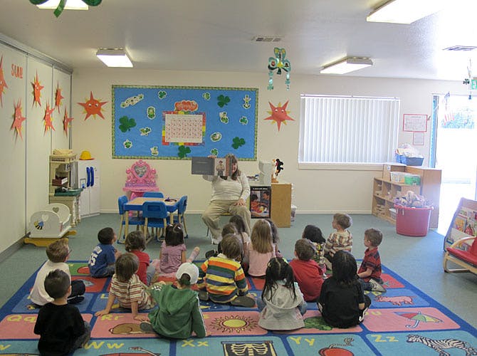 Adult reading to children sitting on a rug in a classroom