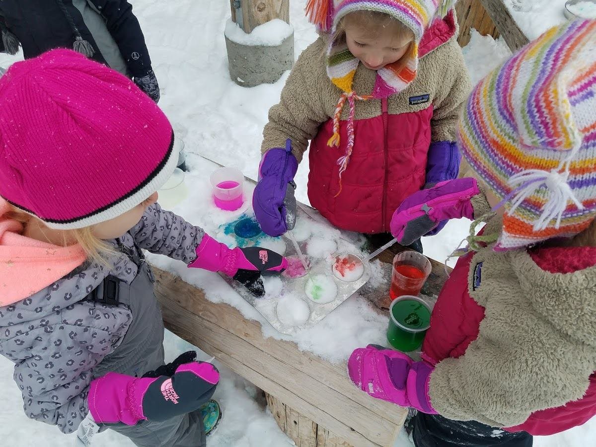 Children playing with snow and colorful liquids outdoors