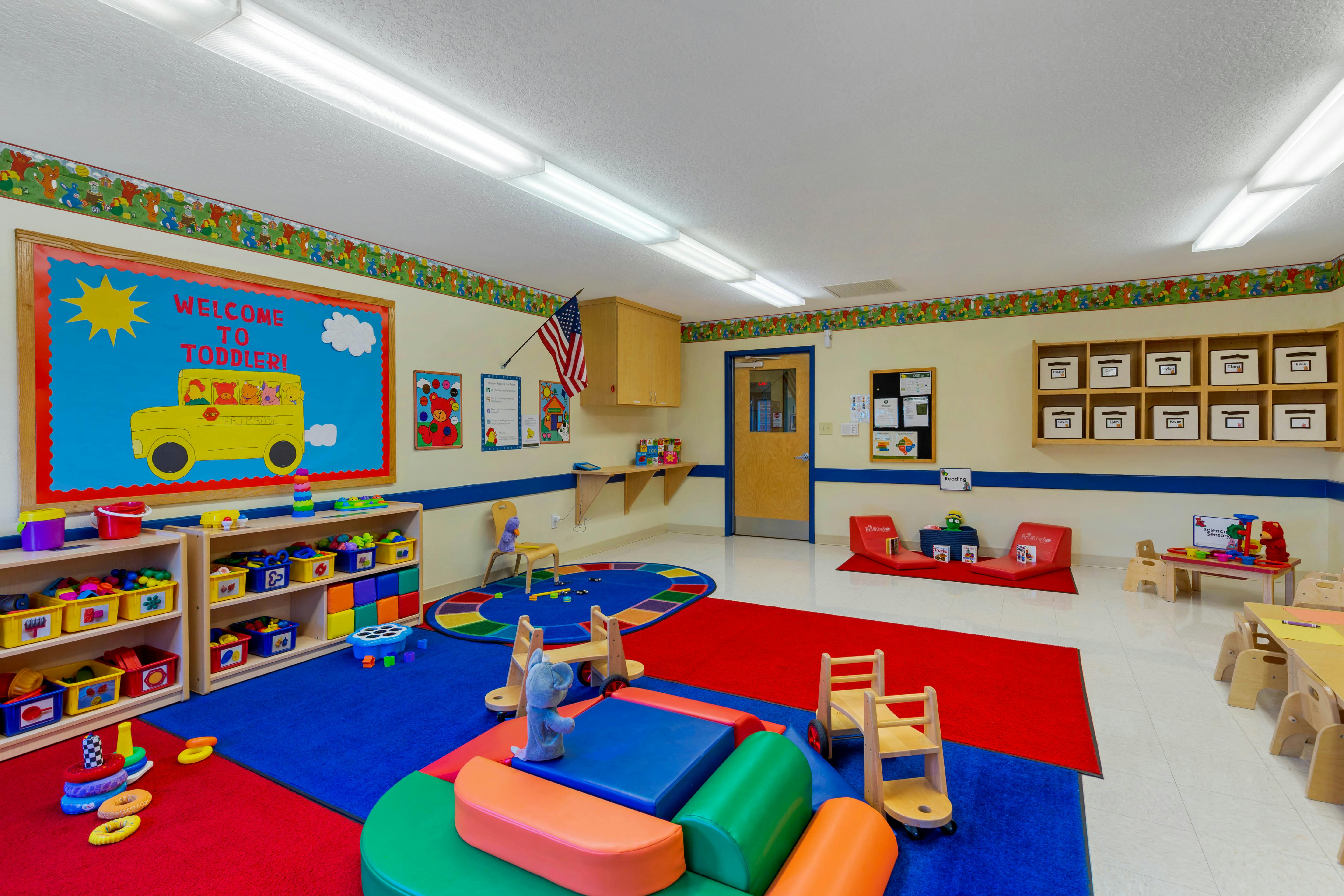 Colorful playroom with shelves of toys, small tables, chairs, and rugs