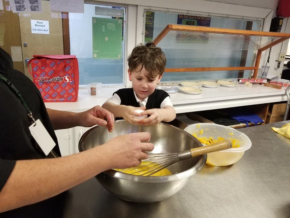 Person and child mixing ingredients in a bowl in a kitchen
