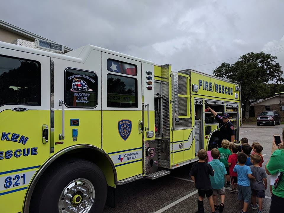 Children gathered around a fire truck with a person in uniform