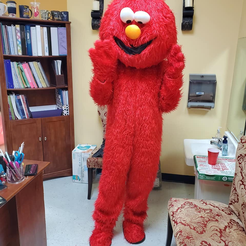 Person in a red furry costume with large eyes and an orange nose