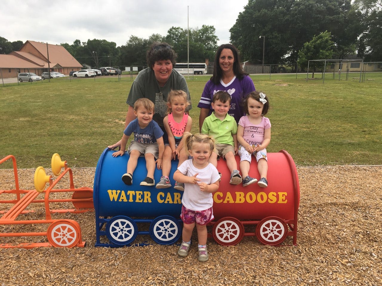 Two adults and five children on a playground train