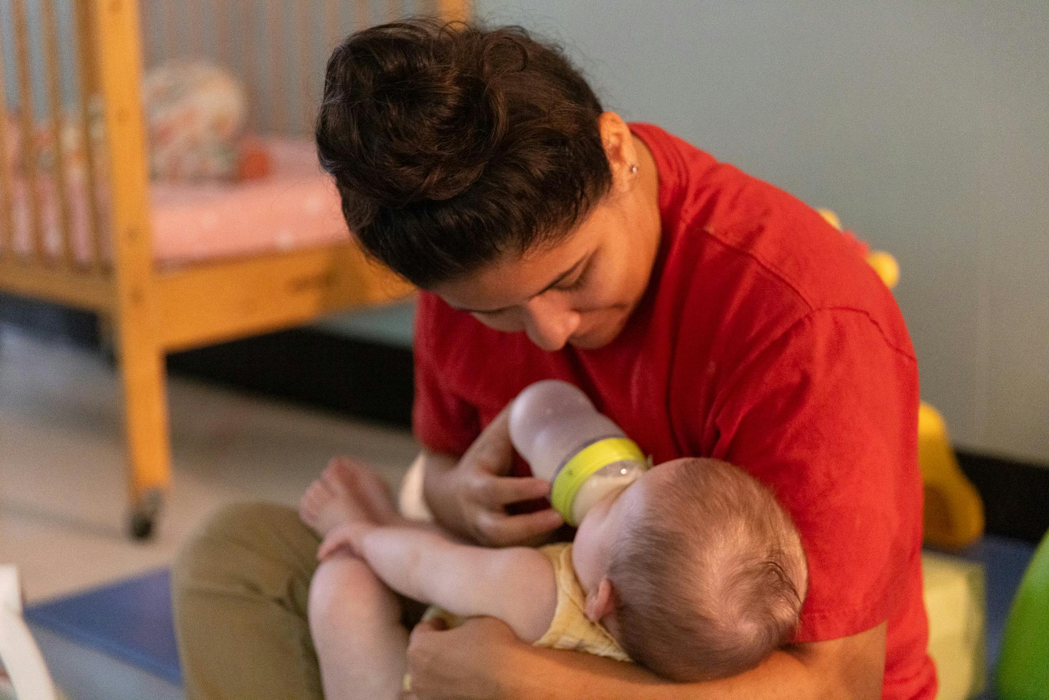 Person feeding a child with a bottle