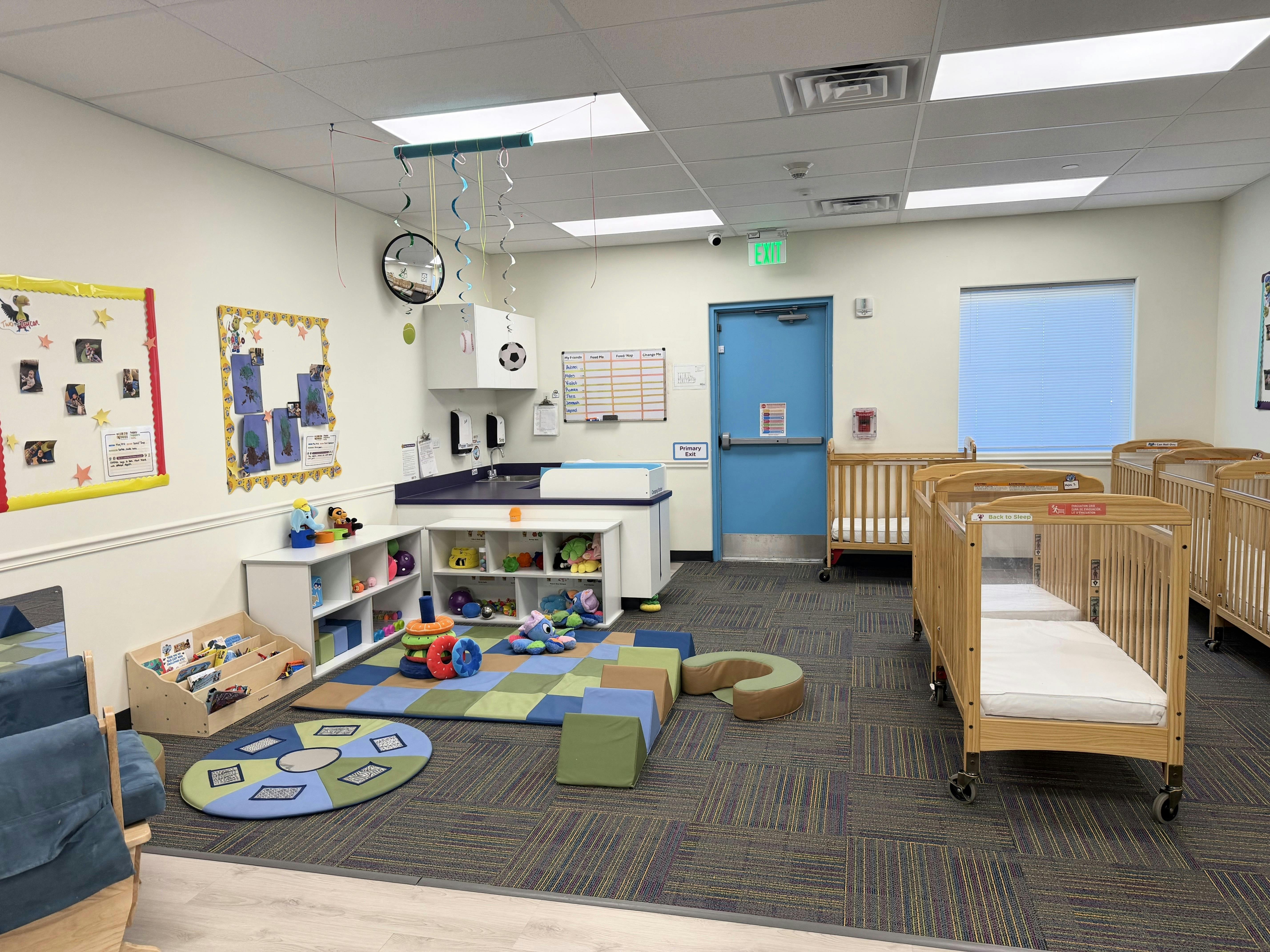A childcare room with multiple cribs, a changing station, and play areas