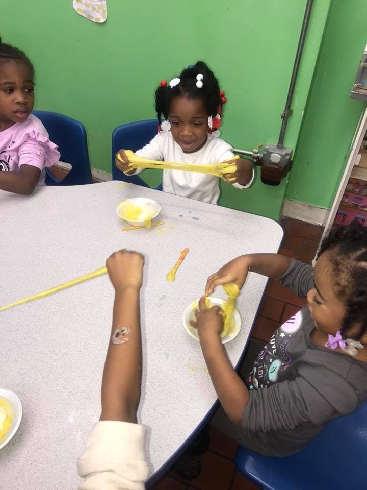 Children playing with yellow slime at a table