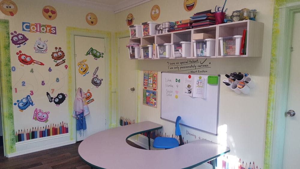 Classroom with a curved table, whiteboard, and colorful wall decorations