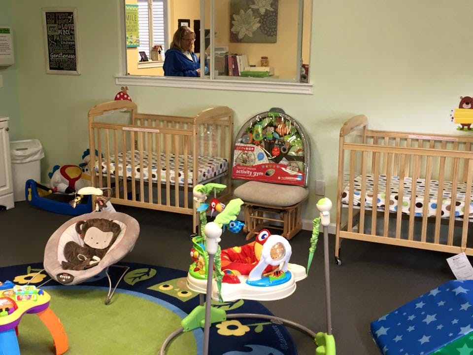 Nursery room with two cribs, baby bouncer, and play mats