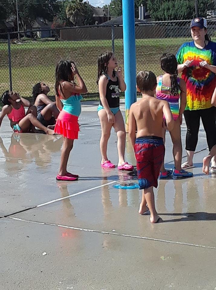 Children and an adult on a wet splash pad