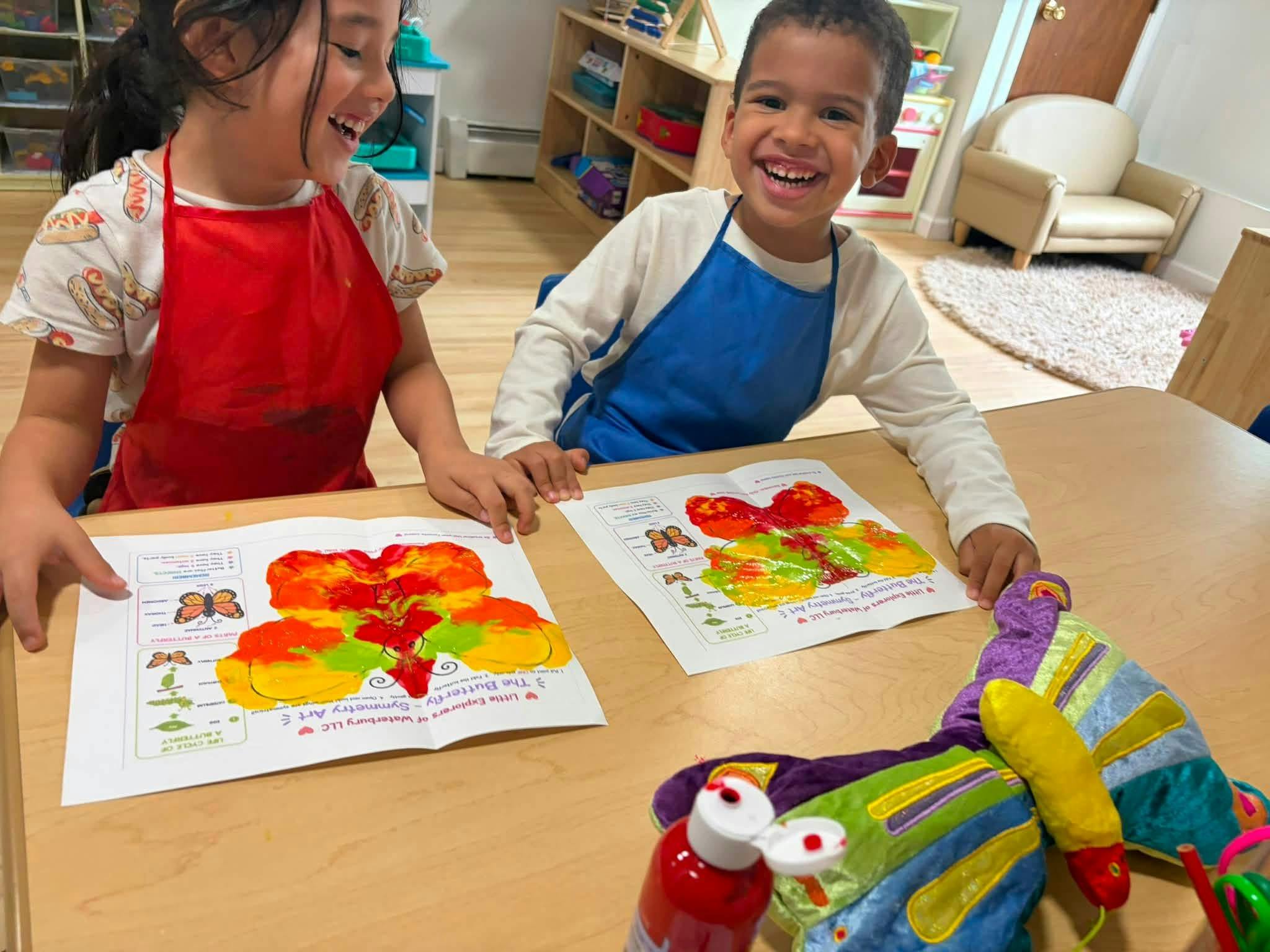 Two children creating butterfly symmetry art at a table