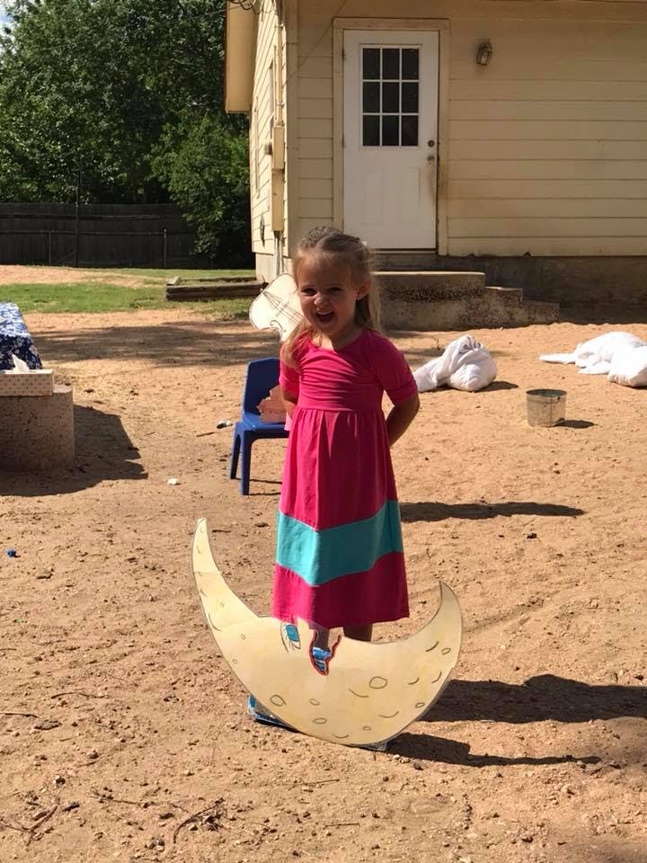 Child standing on a crescent moon prop outdoors