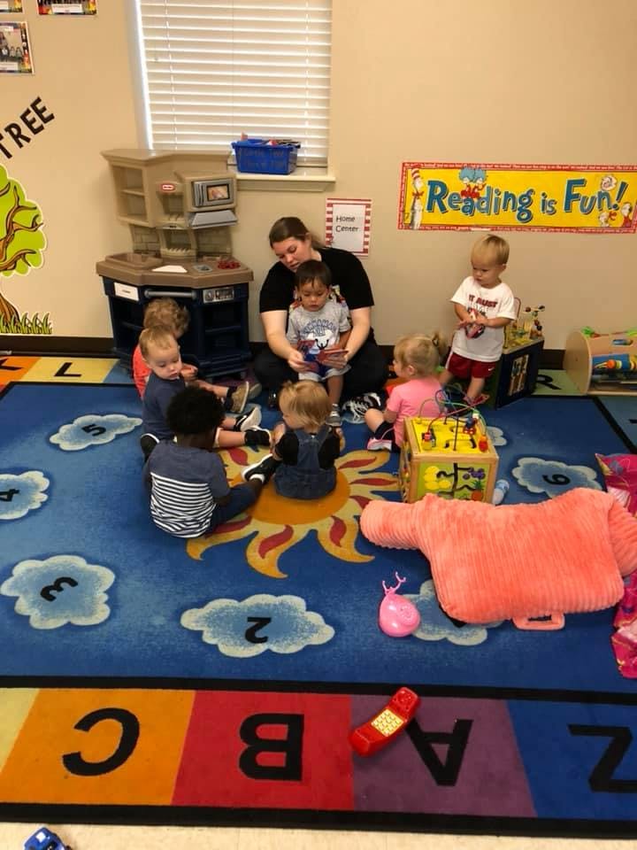 Adult and children sitting on a rug in a classroom