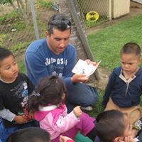 Adult reading a book to children outdoors