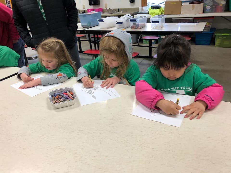 Three children drawing at a table