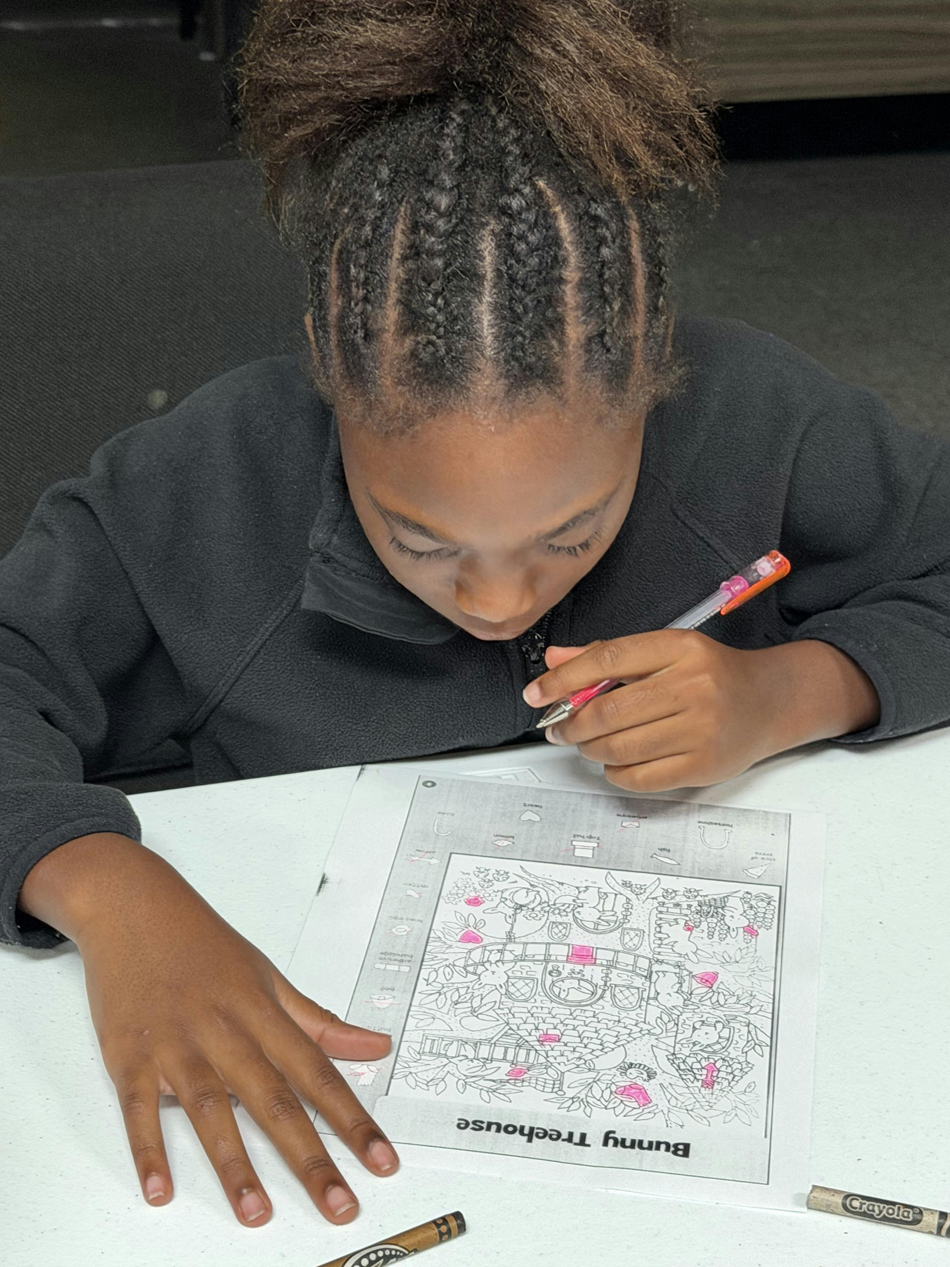 Child coloring a Bunny Treehouse activity sheet at a table