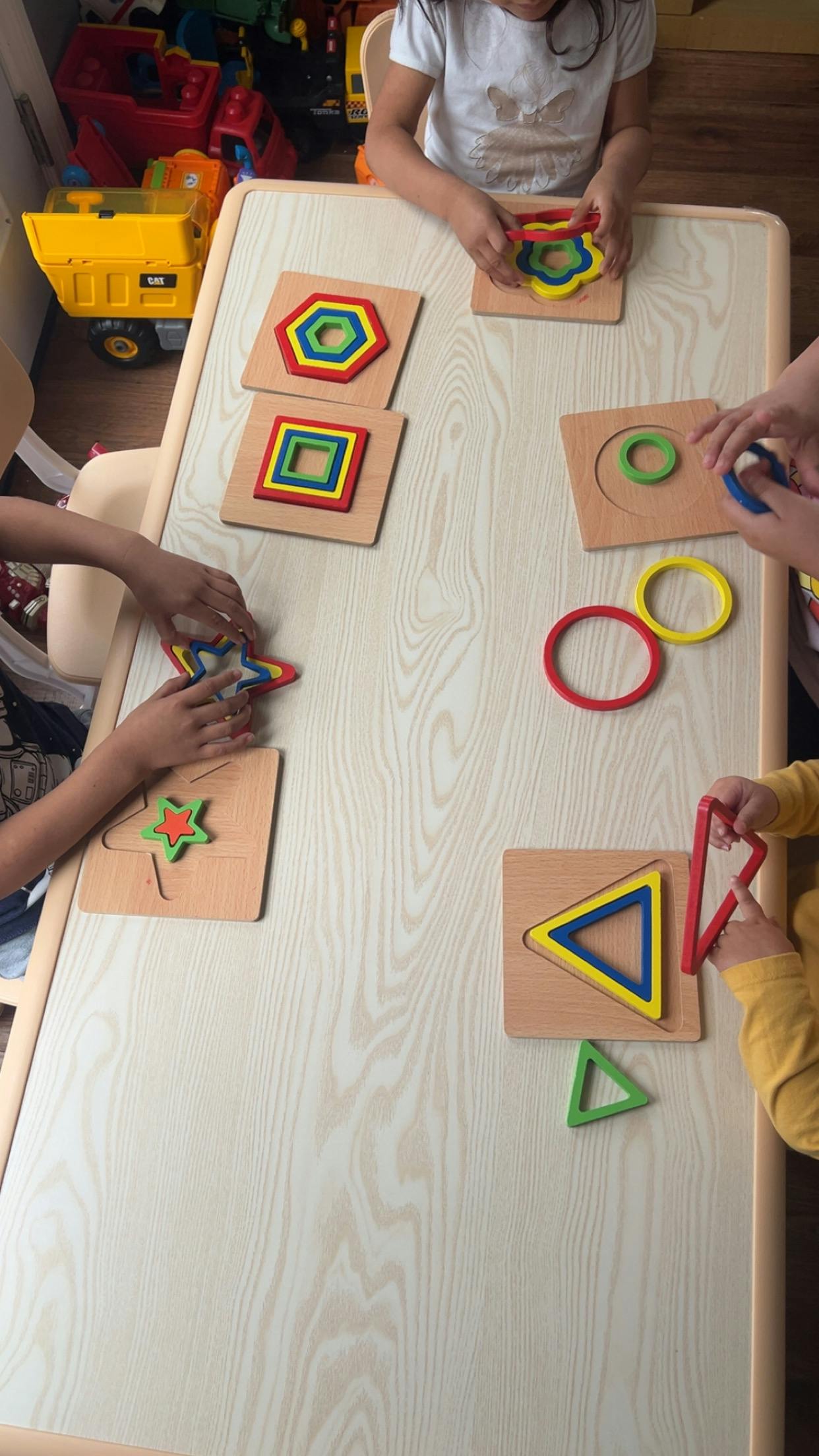 Multiple children playing with colorful wooden shape puzzles at a table