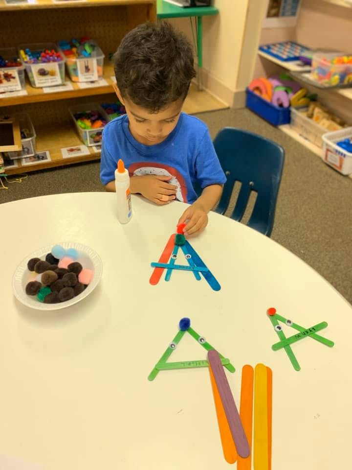 Child making crafts with popsicle sticks and googly eyes