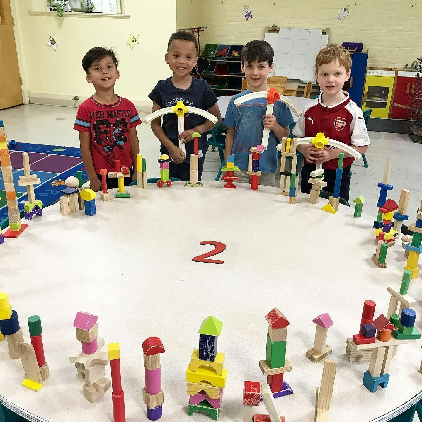 Four children standing around a table with wooden blocks