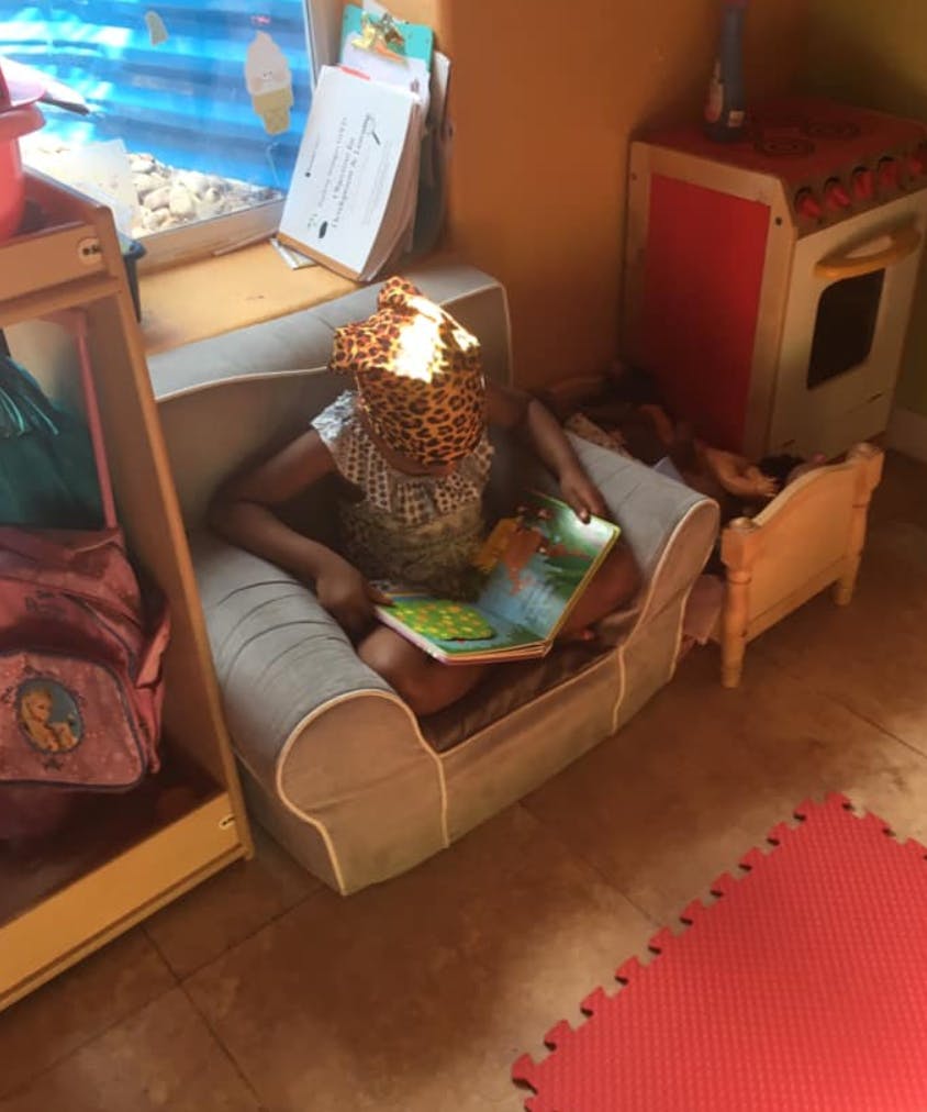 Child sitting on a small couch reading a book