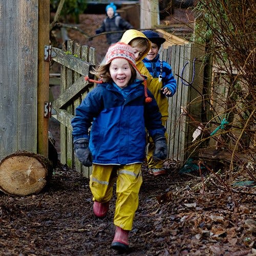 Children running outside through a muddy path