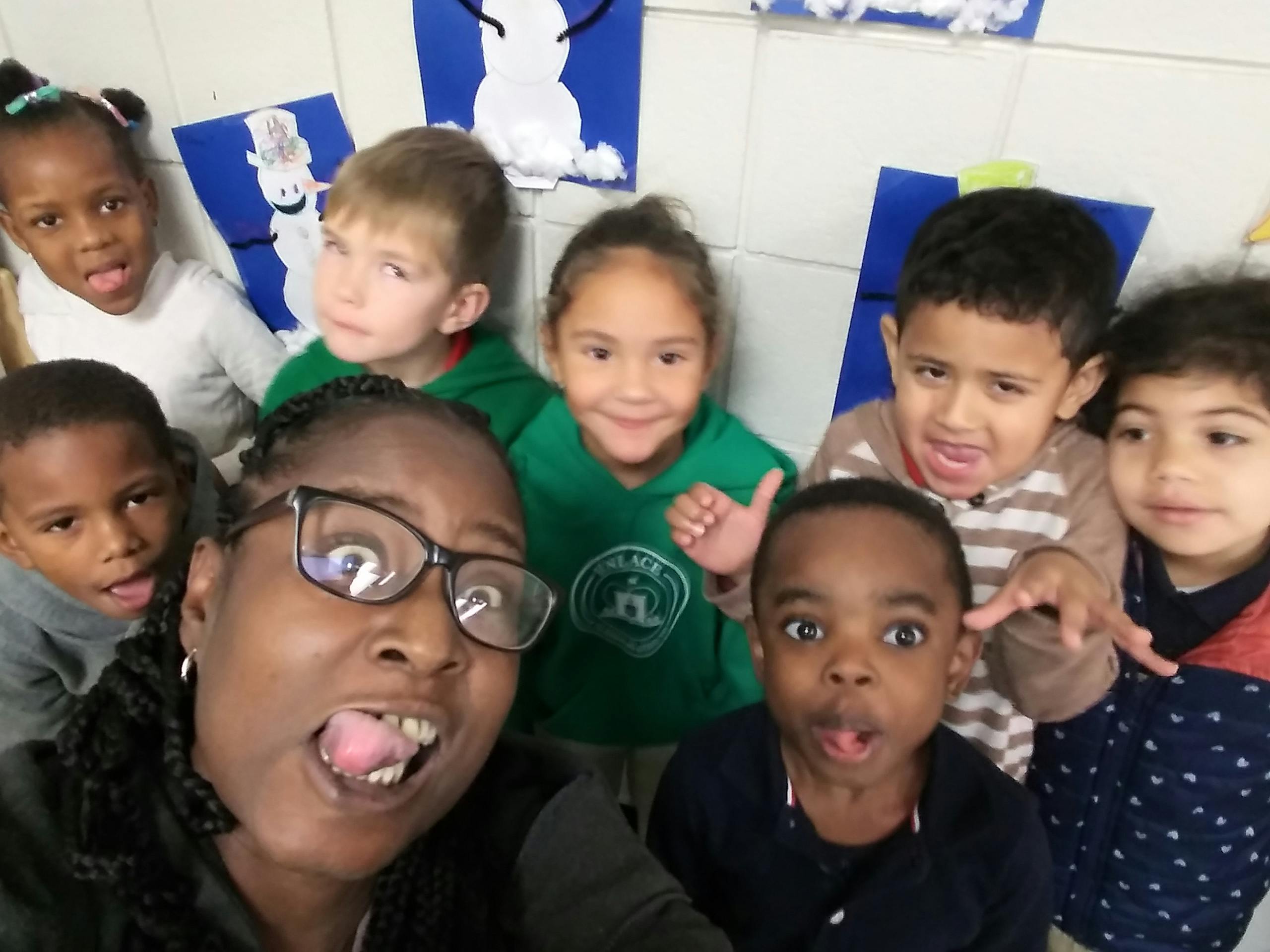 Person with glasses and several children making funny faces