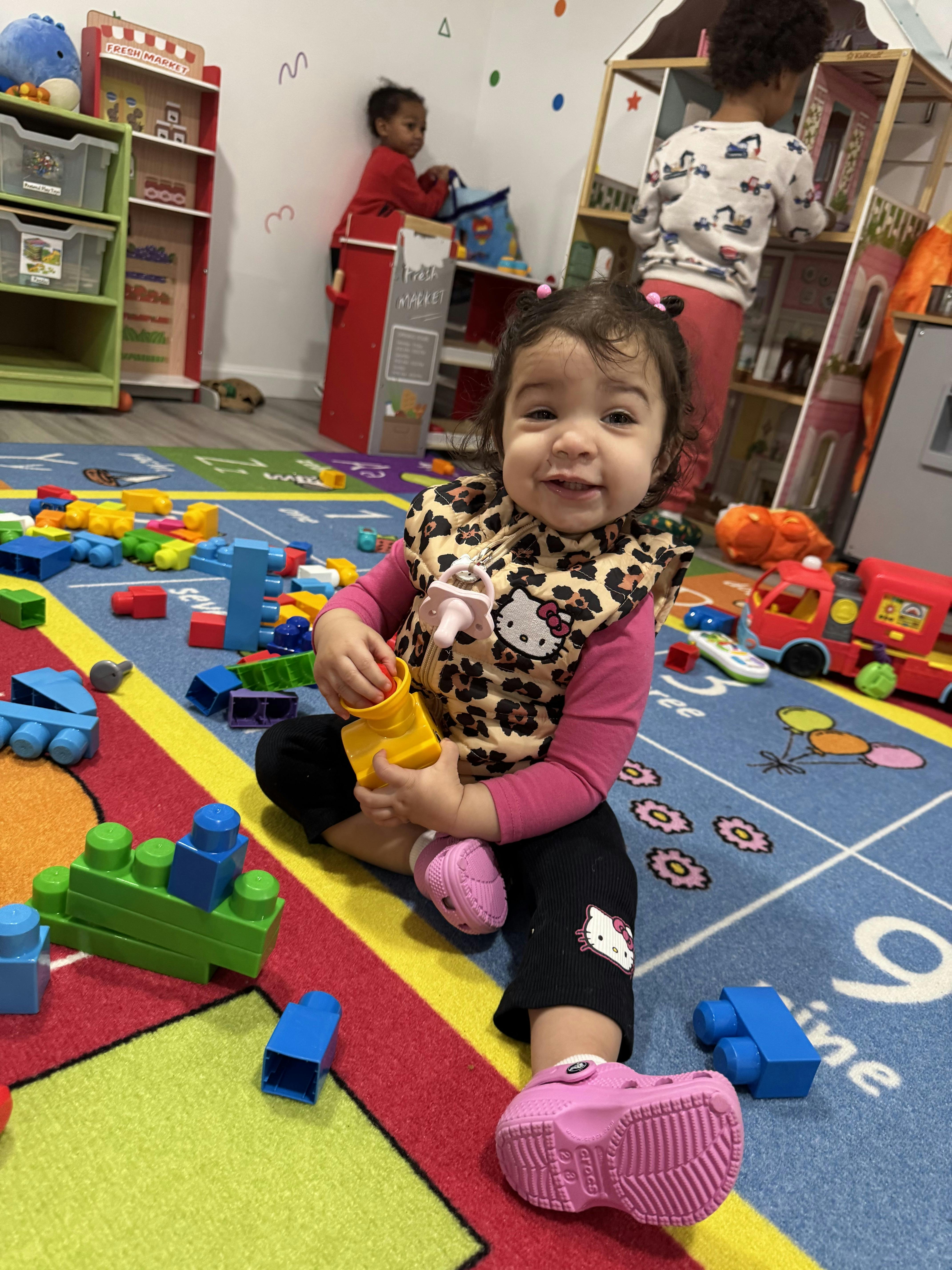 A child sitting on a colorful mat playing with large building blocks