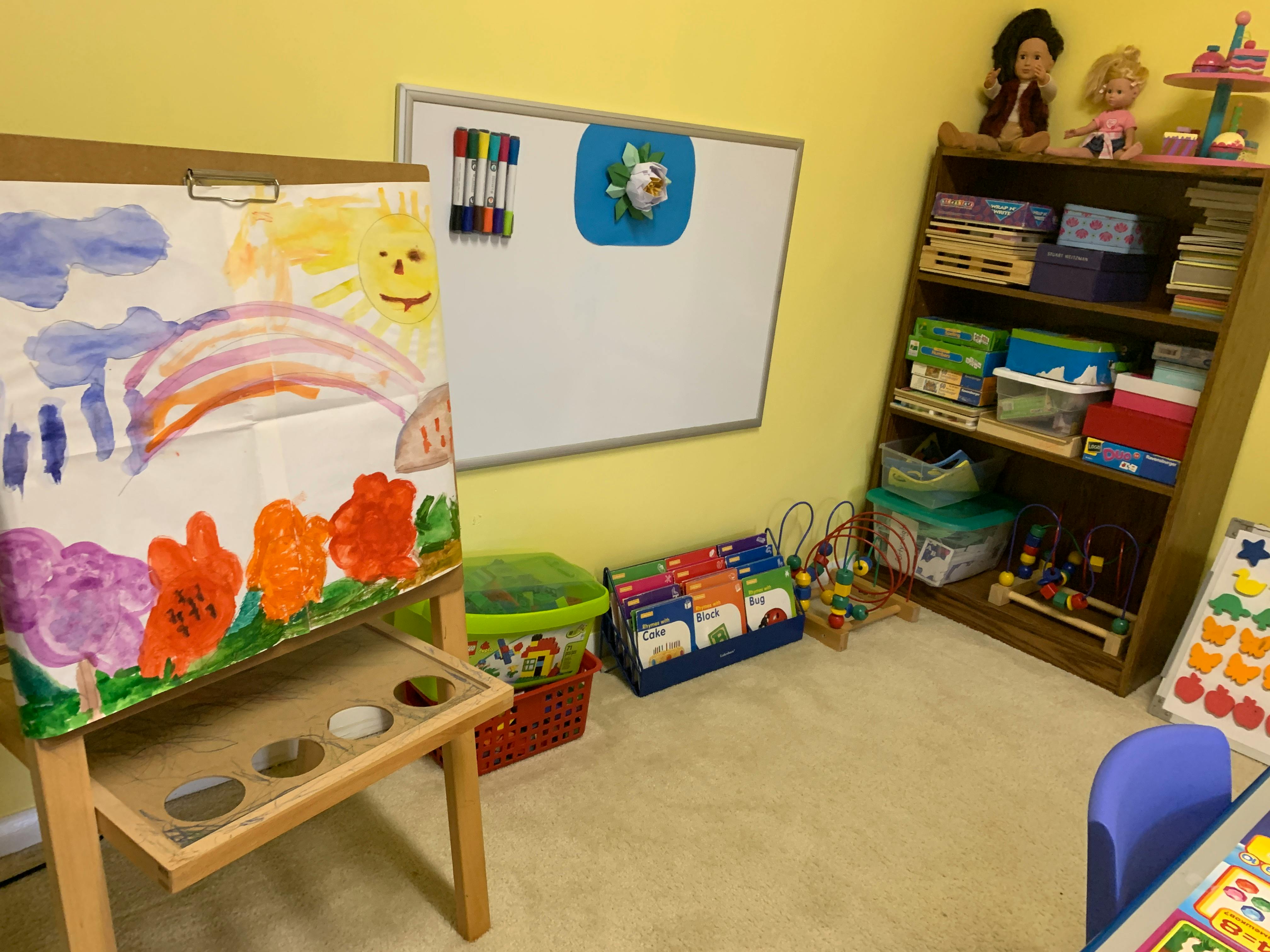 Child's painting on an easel with a rainbow, sun, and flowers