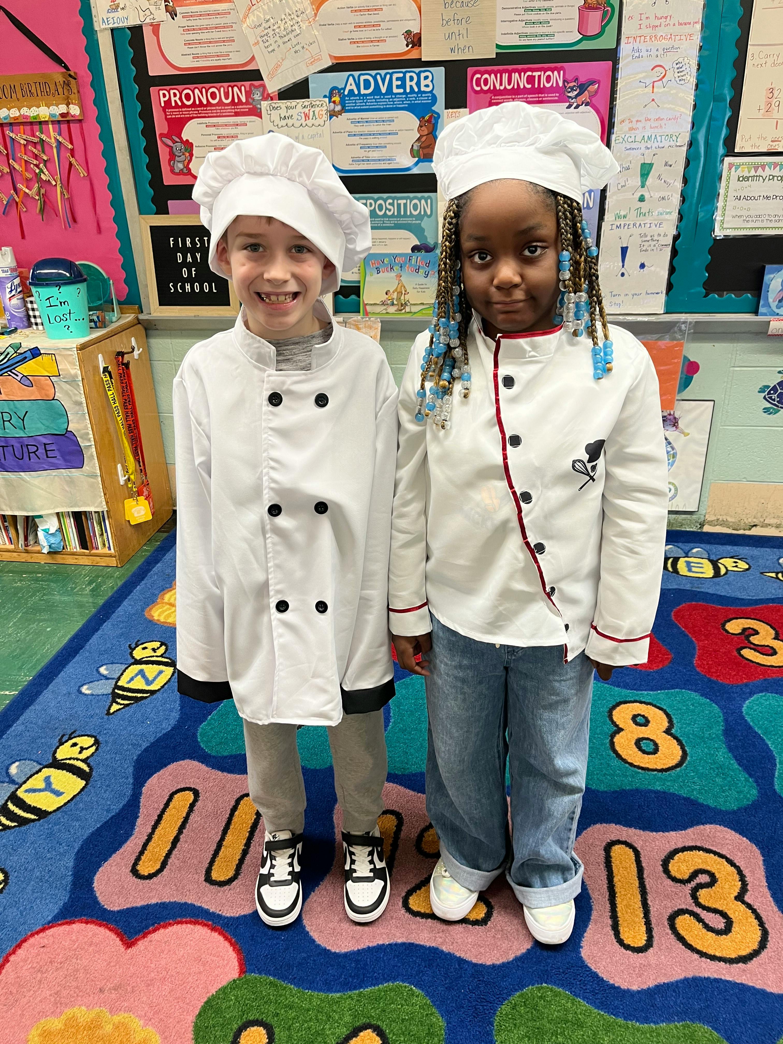 Two children in chef costumes standing in a classroom