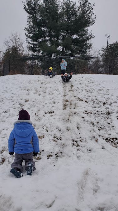 Children playing in the snow on a hill