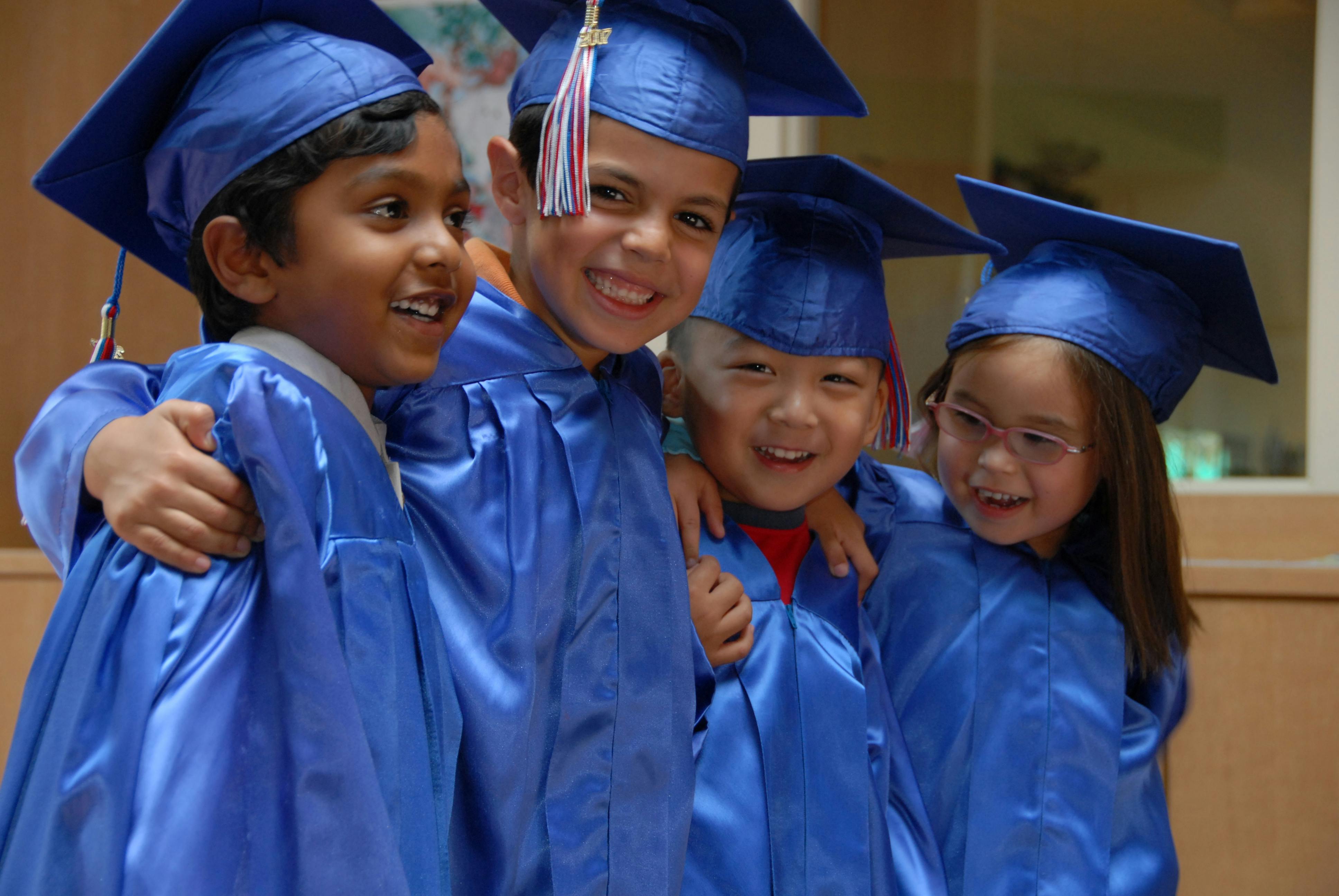 Four children in blue graduation caps and gowns