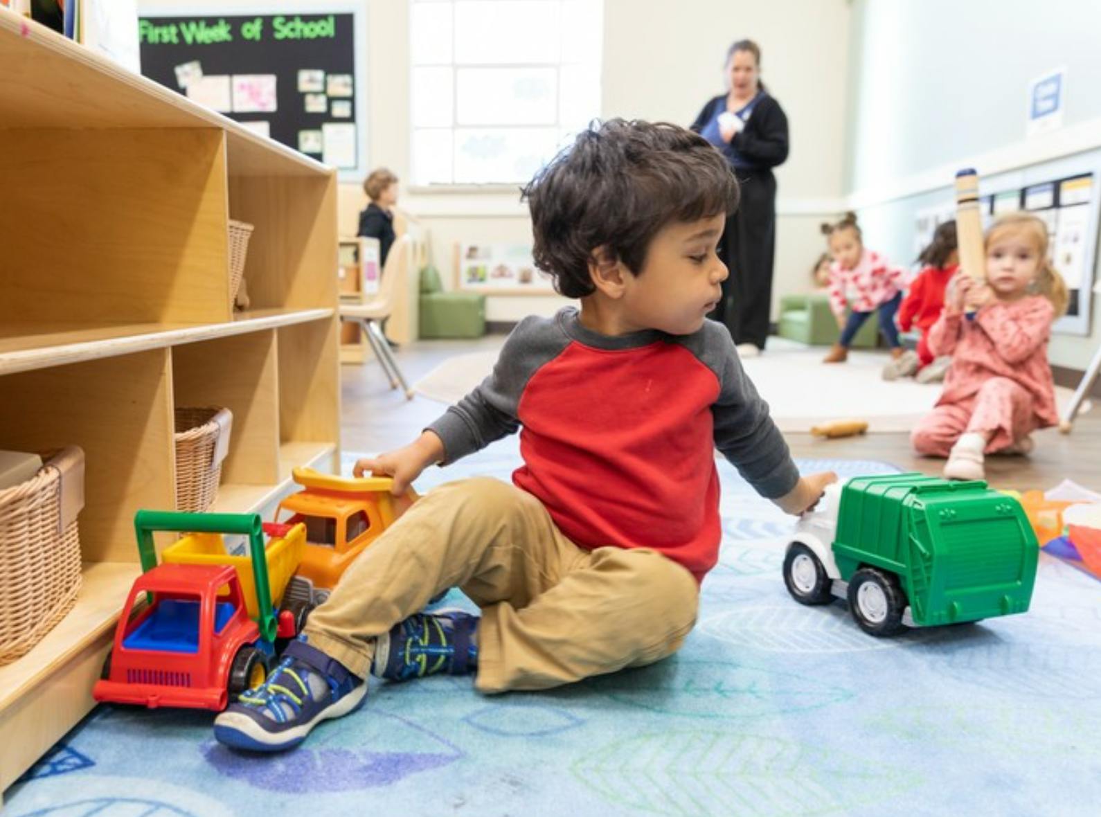 Child playing with toy trucks on a classroom floor