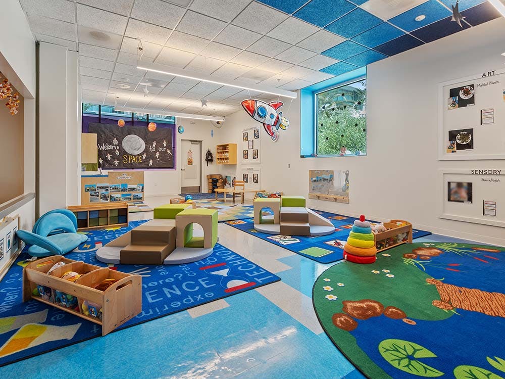 Playroom with multiple activity areas and colorful rugs