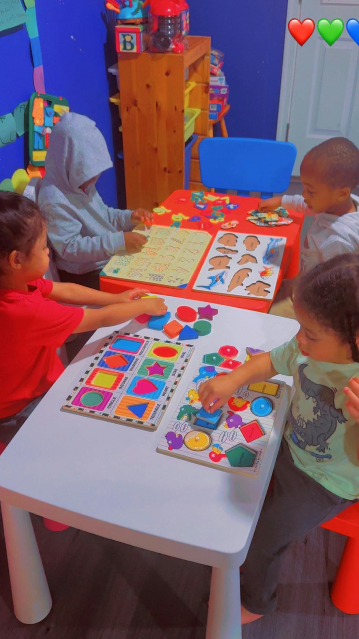 Four children playing with shape and animal puzzles at tables