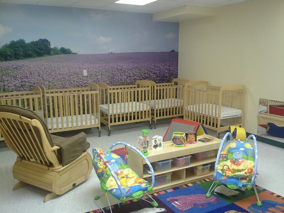 Nursery room with multiple cribs, a rocking chair, and play items