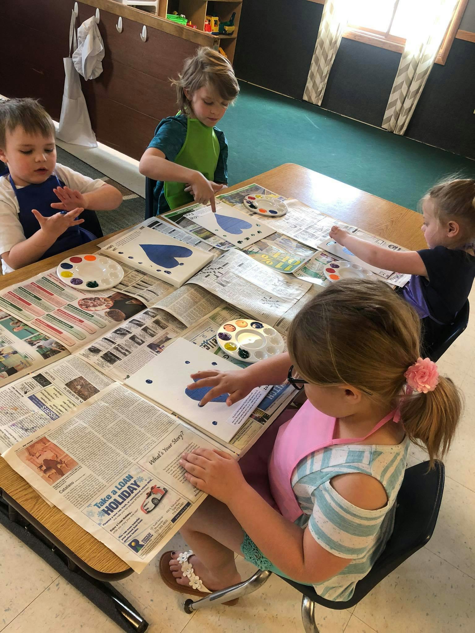 Children painting heart shapes in a classroom