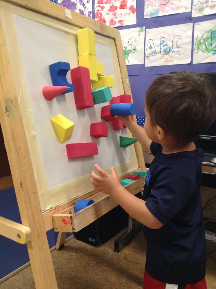 Child playing with colorful magnetic blocks on an easel