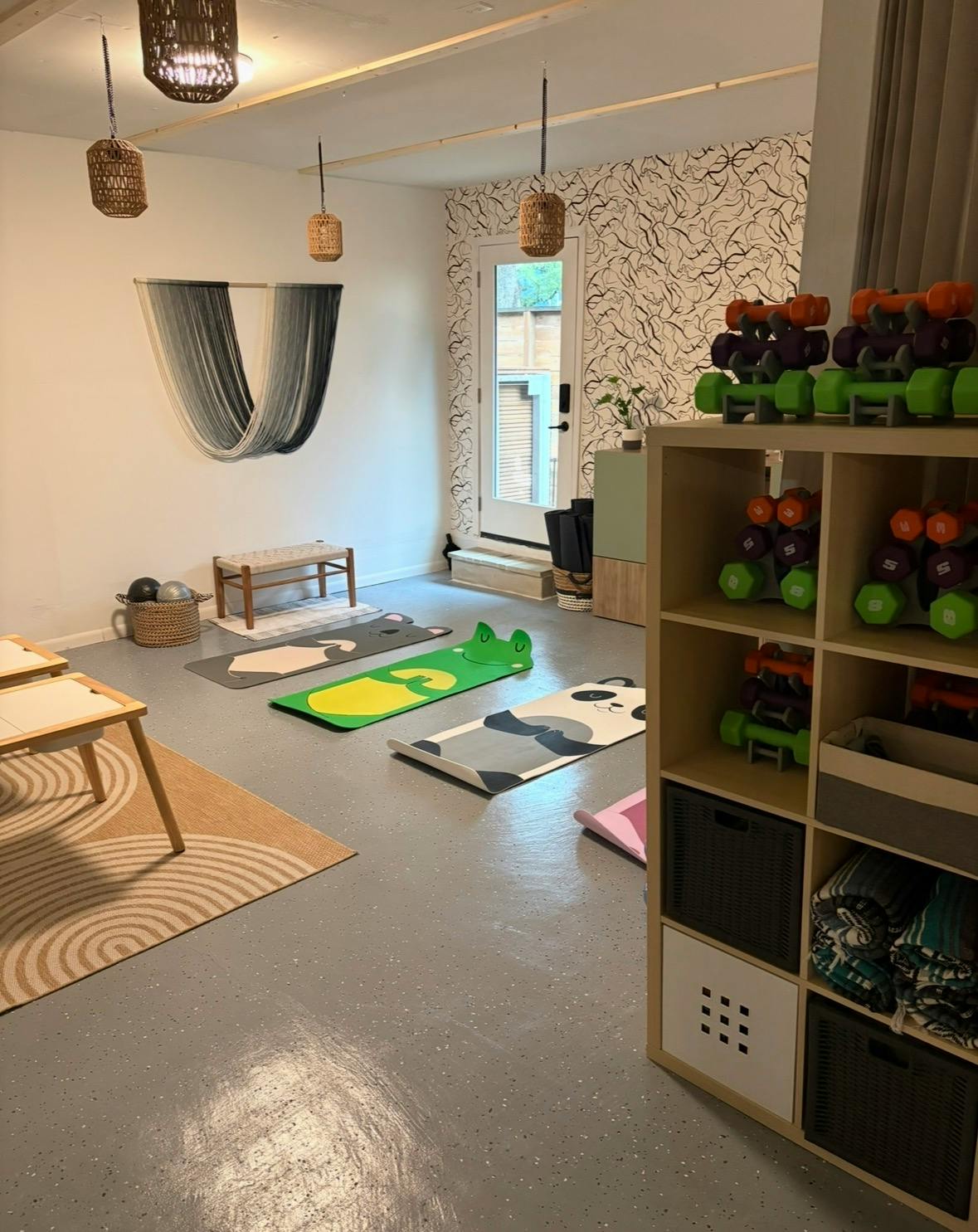 Exercise room with animal themed yoga mats and a storage shelf of dumbbells