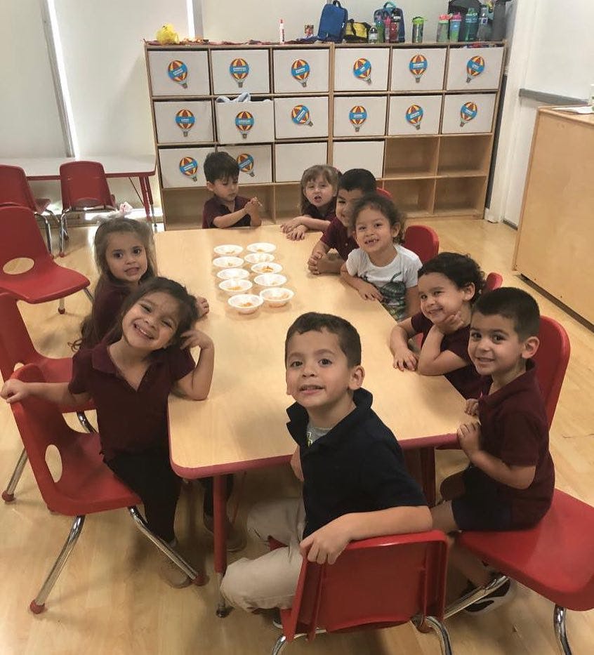 Children sitting at a table with bowls in a classroom