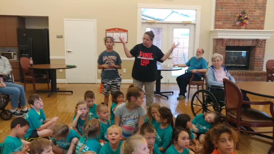 Adult speaking to a group of children and adults