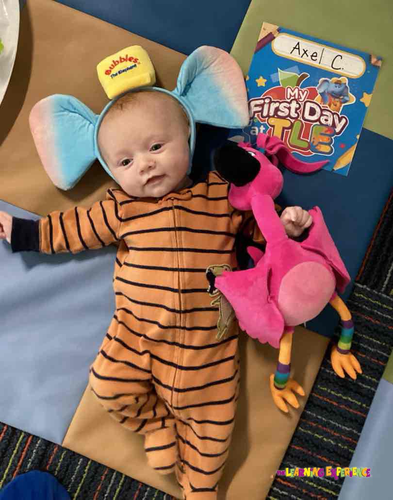 Child in striped pajamas and elephant ears headband with a pink flamingo toy