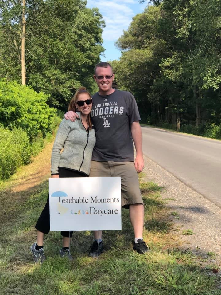 Two people holding a sign that says "Teachable Moments Daycare"