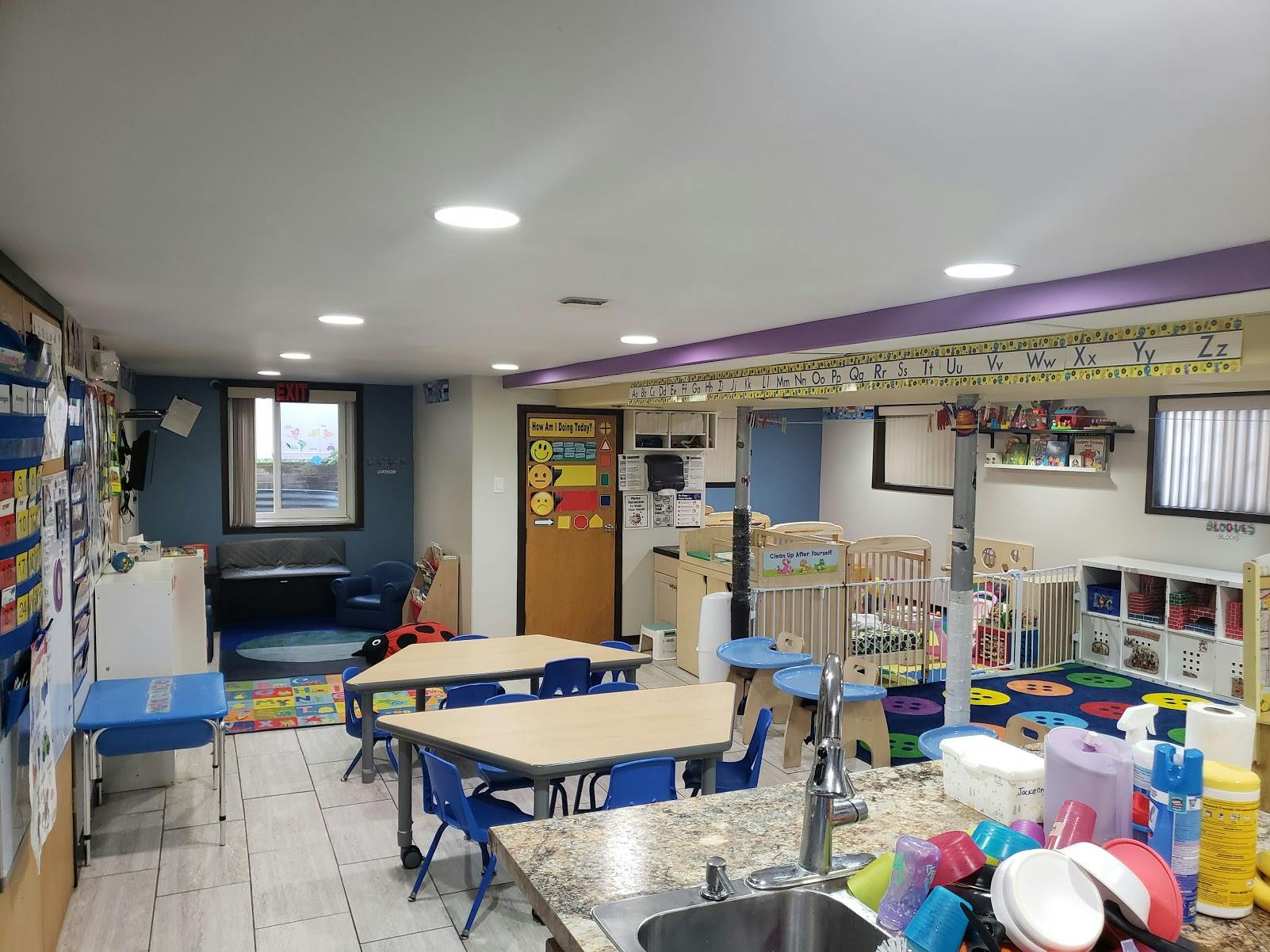 Daycare room with tables, chairs, and cribs