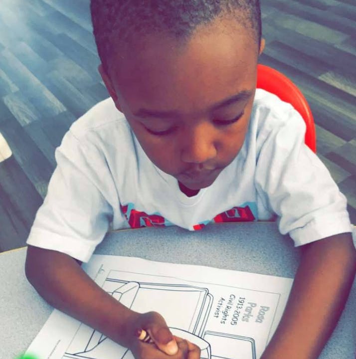 Child coloring a picture on a paper with a crayon