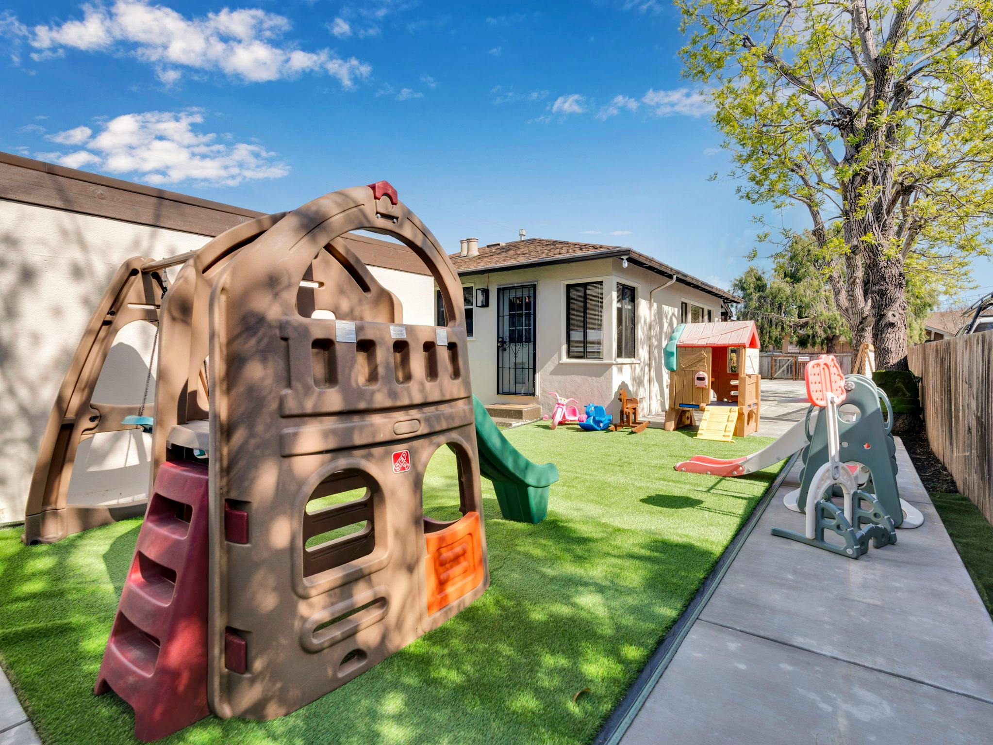 Outdoor playground with a large play structure and slide on artificial turf
