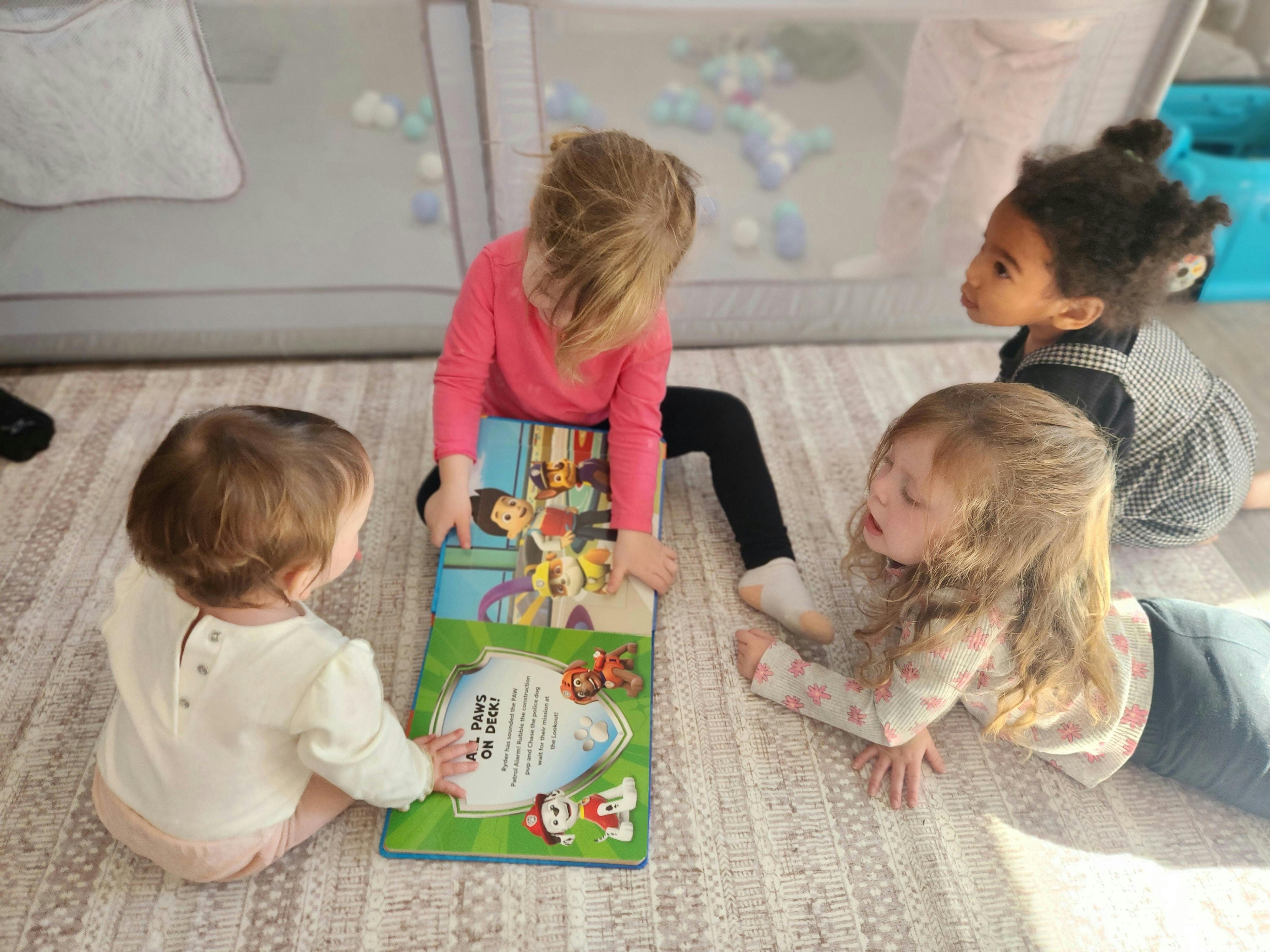 Four children looking at a book on the floor