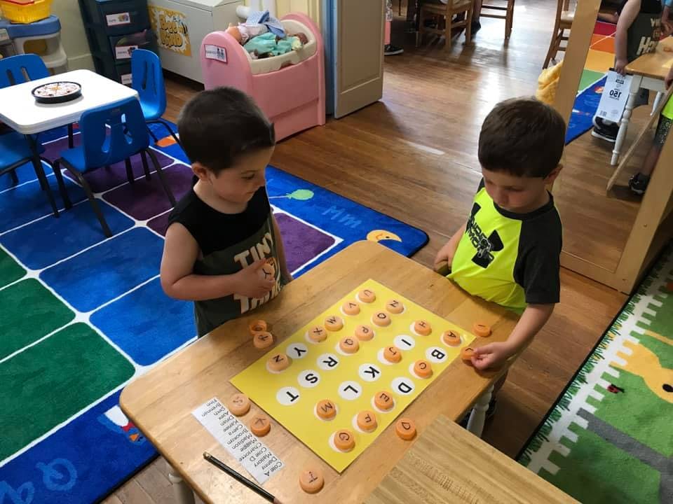 Two children playing a letter matching game in a classroom