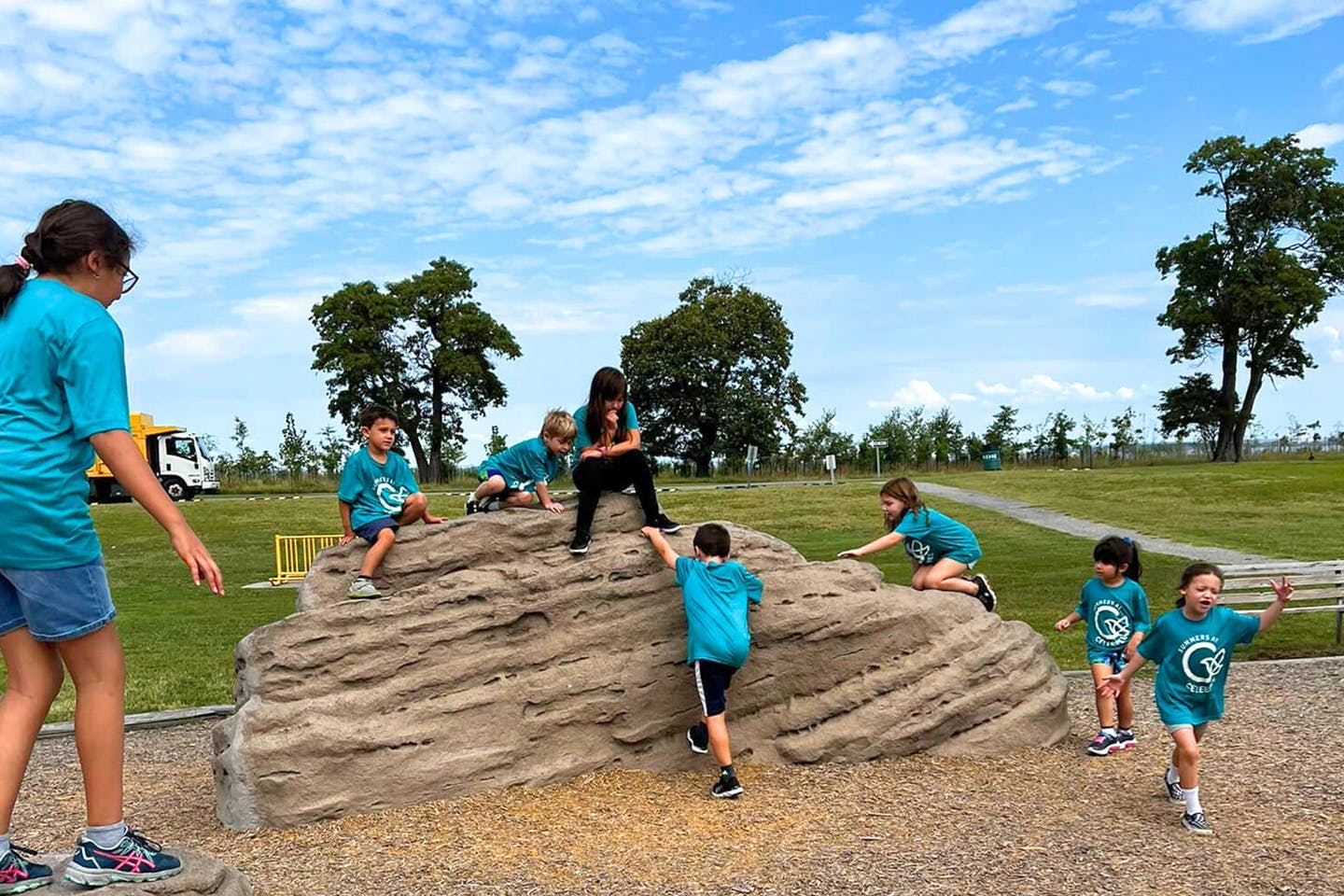 Children and adults climbing on a large rock formation outdoors