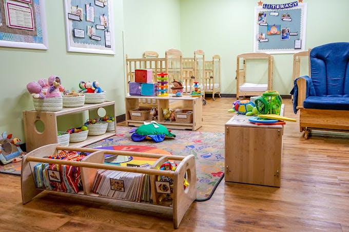 Baby and toddler classroom with cribs, play mats, and learning toys